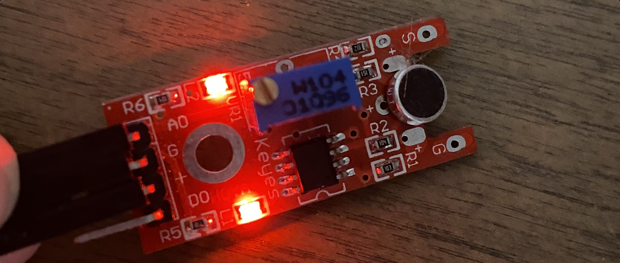 Close-up of the Arduino Sound Sensor, a small red device with a circular black microphone